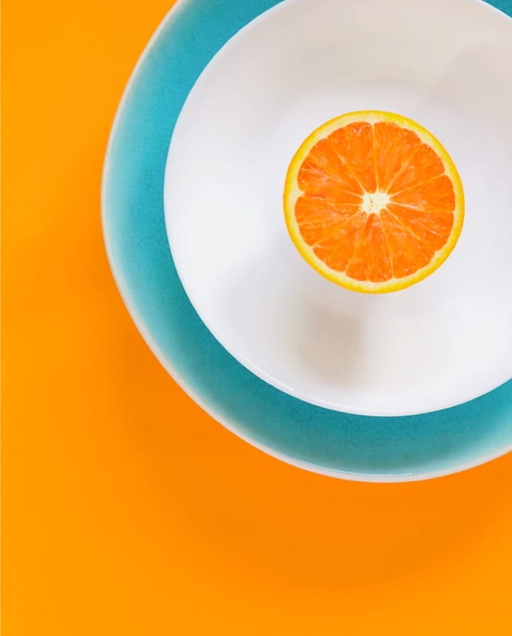 cut orange in the middle of a plate on orage background