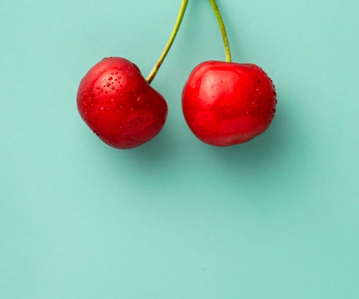 2 cherries on green background